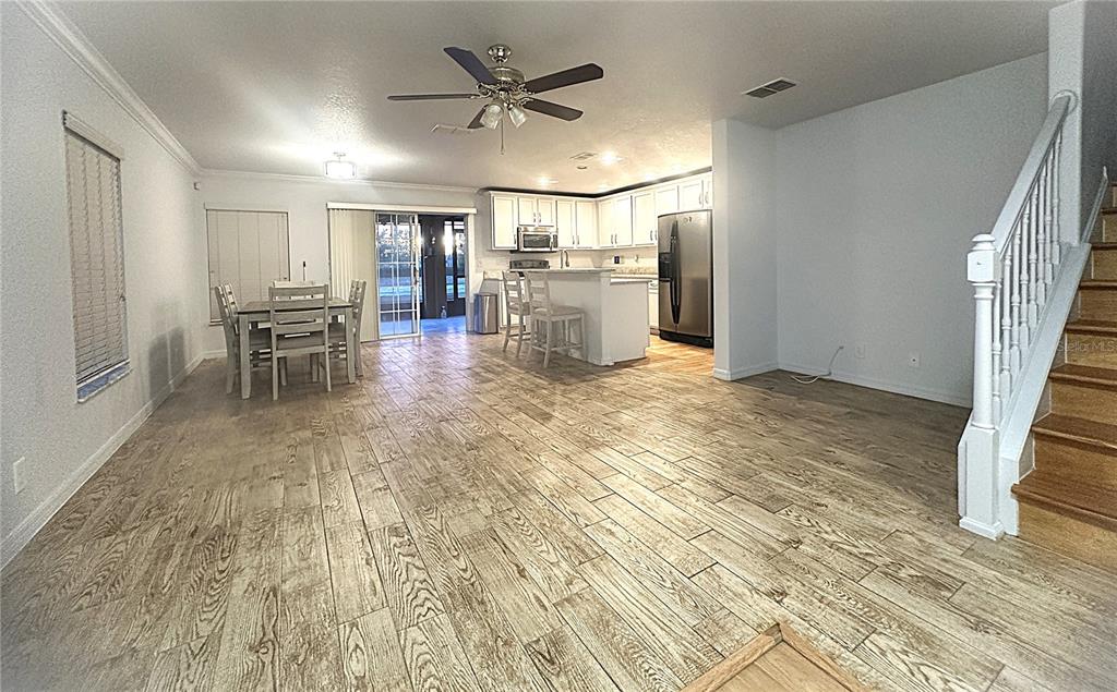 An open-concept kitchen and dining area features wood-look tile flooring and a staircase — 2048 SUN DOWN DRIVE, CLEARWATER, FL