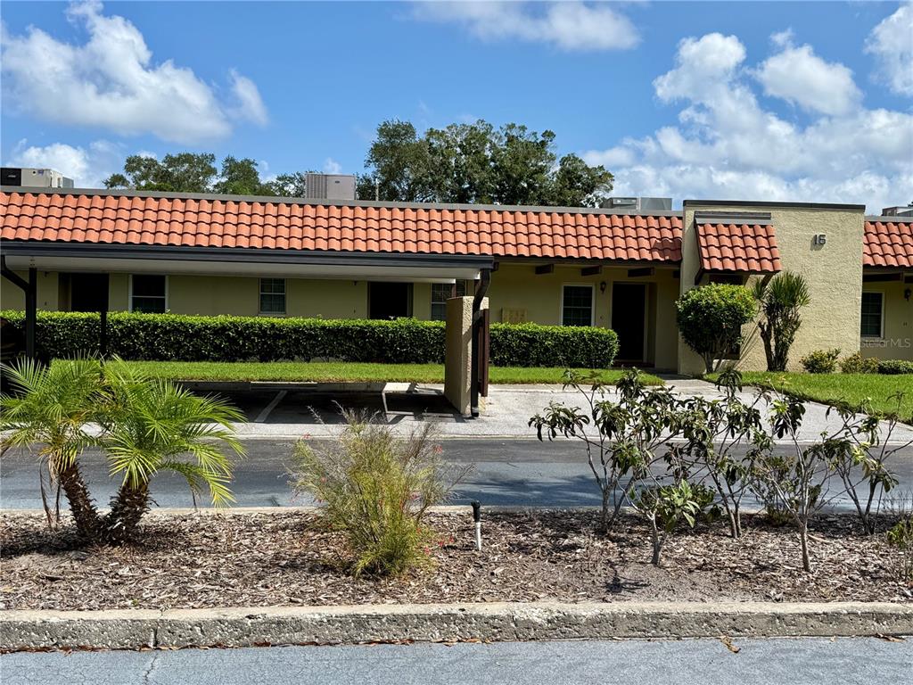 A single-story building with a red tile roof and a covered parking area — 1701 PINEHURST ROAD UNIT 16G, DUNEDIN, FL