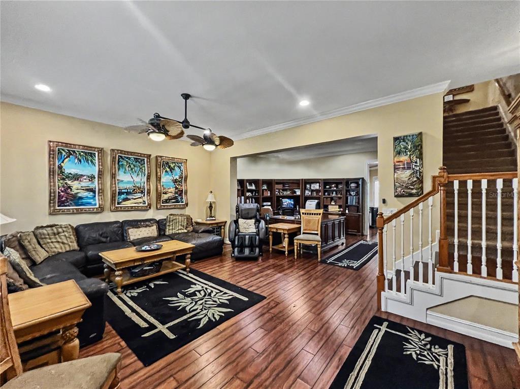 A living room with dark wood floors, a leather sectional, and a staircase — 1208 CELEBRATION AVENUE, CELEBRATION, FL