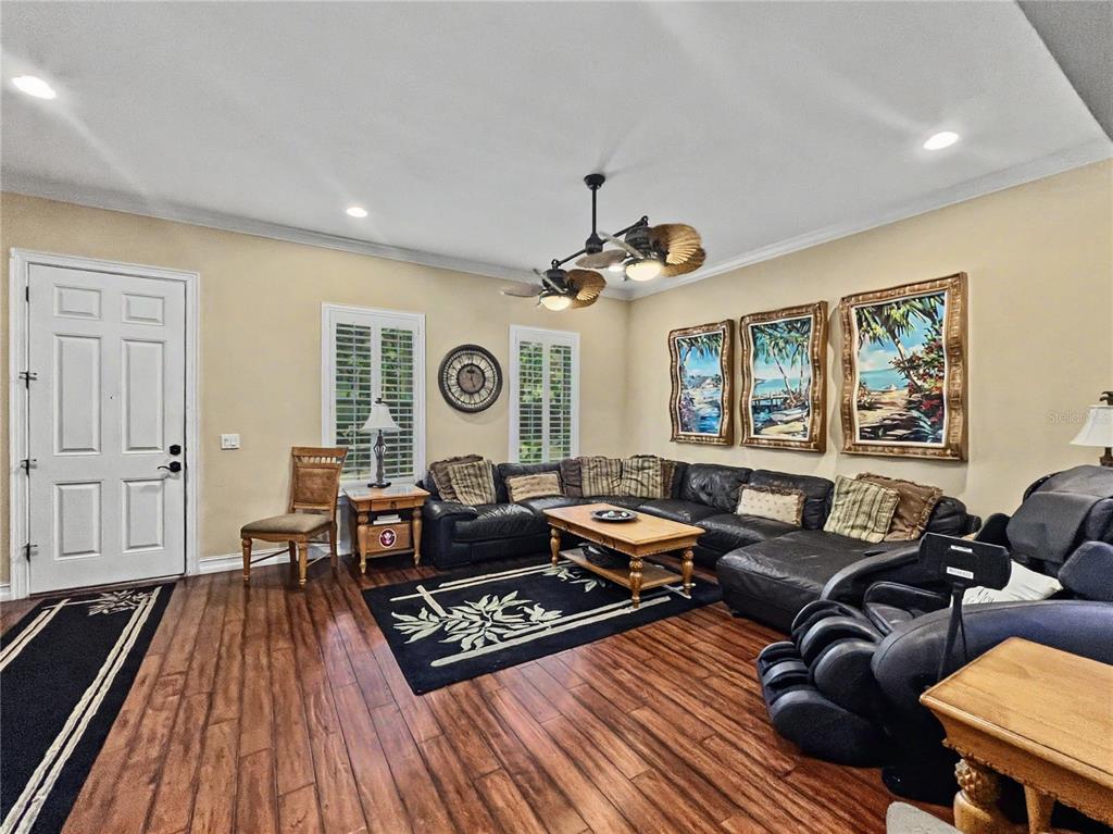 A living room features dark leather sectional seating, a wooden coffee table, and wood flooring — 1208 CELEBRATION AVENUE, CELEBRATION, FL
