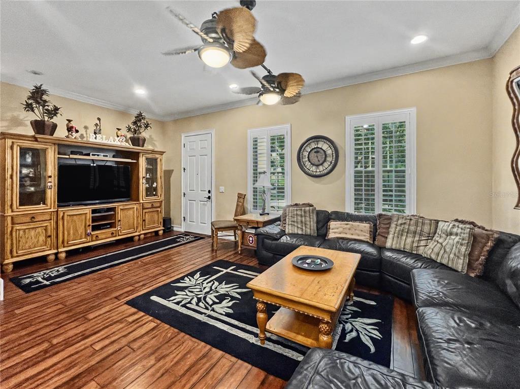 A living room features a black leather sectional, wooden entertainment center, and two ceiling fans — 1208 CELEBRATION AVENUE, CELEBRATION, FL