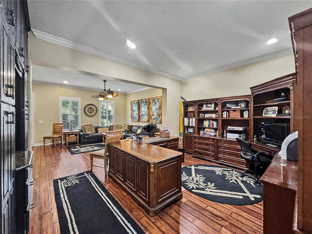 A spacious home office features dark wood furniture, built-in shelving, and hardwood flooring — 1208 CELEBRATION AVENUE, CELEBRATION, FL