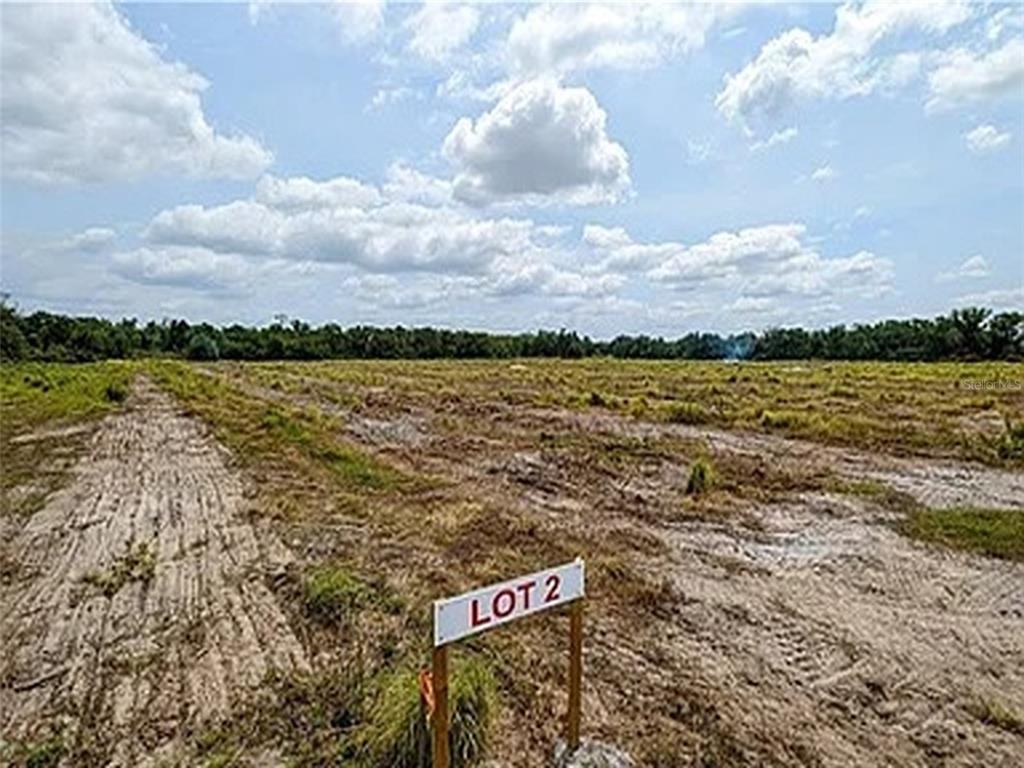 A sign labeled Lot 2 stands in a cleared, grassy field under a cloudy sky — KEENTOWN ROAD, PARRISH, FL