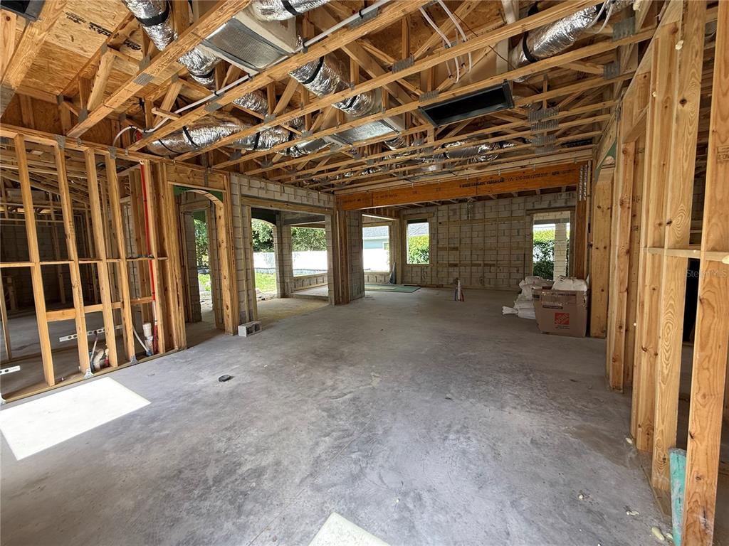 An unfinished room features exposed wooden ceiling joists, concrete block walls, and a sliding glass door — 207 E KINGS WAY, WINTER PARK, FL