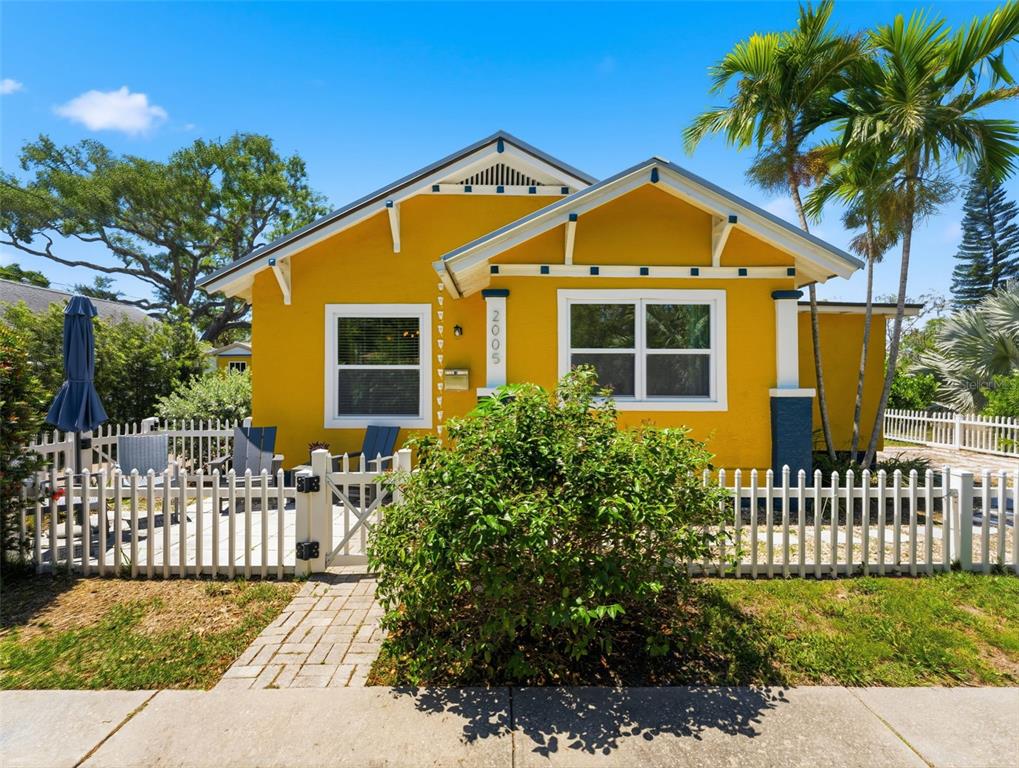 A patio with four chairs and a closed umbrella sits beside a yellow house — 2005 3RD STREET S, ST PETERSBURG, FL