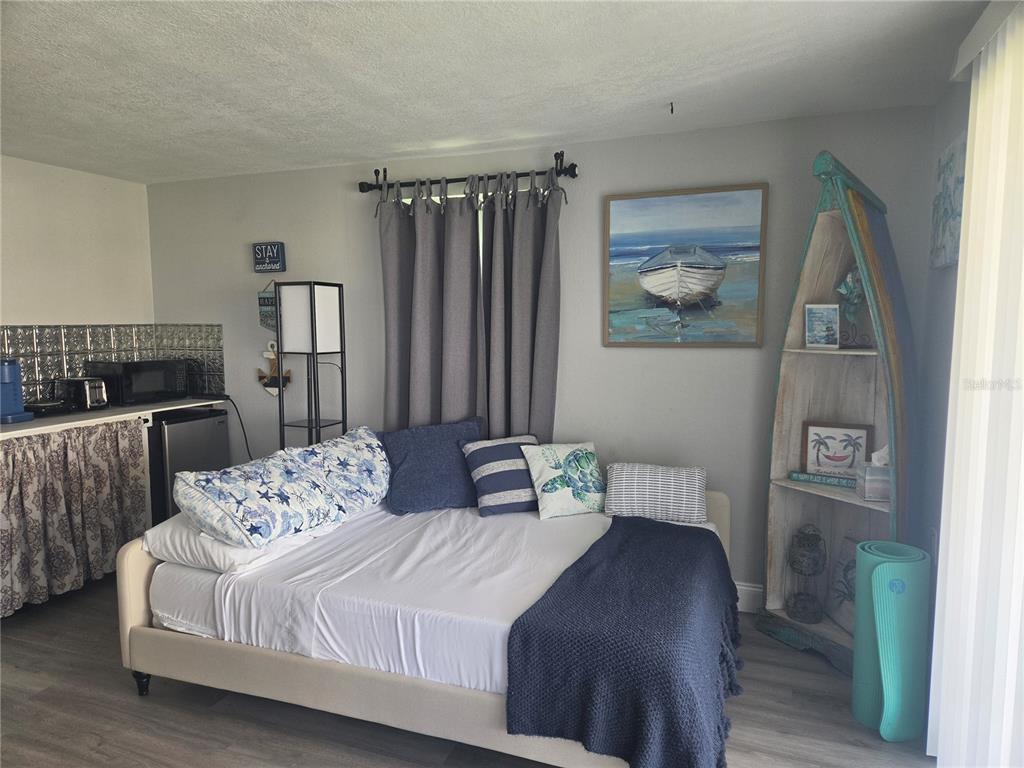 A bedroom features a daybed, a boat-shaped bookshelf, and a small kitchenette area — 12700 5TH ISLE, HUDSON, FL