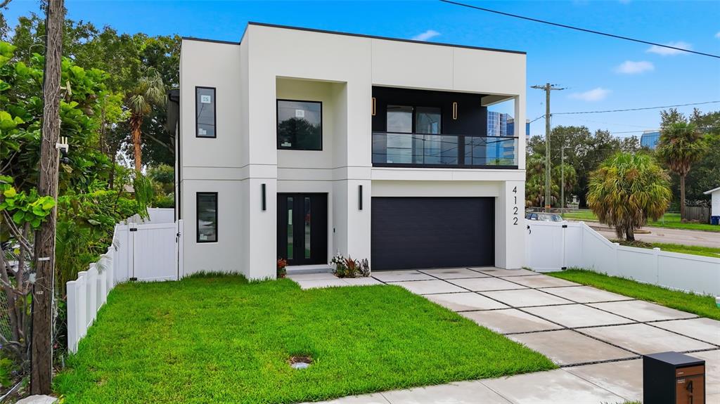 A modern two-story house with a white exterior, black garage door, and a second-floor balcony — 4122 W NASSAU STREET, TAMPA, FL