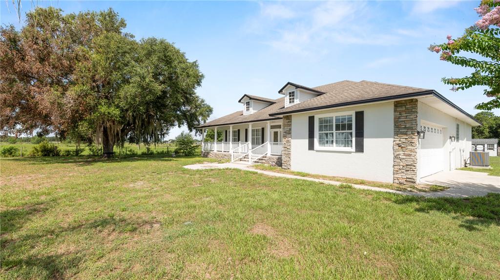 A white house with a stone foundation and a large oak tree in the yard — 611 MORGAN ROAD, WINTER HAVEN, FL