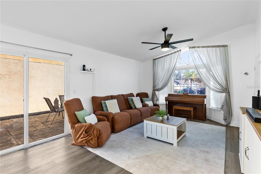 A living room features a brown sofa, a recliner, a piano, and a sliding glass door — 421 HORIZON DRIVE, WINTER SPRINGS, FL