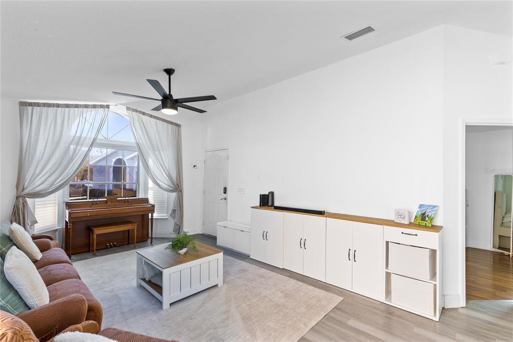 A living room features a brown sofa, a piano, a coffee table, and white storage cabinets — 421 HORIZON DRIVE, WINTER SPRINGS, FL