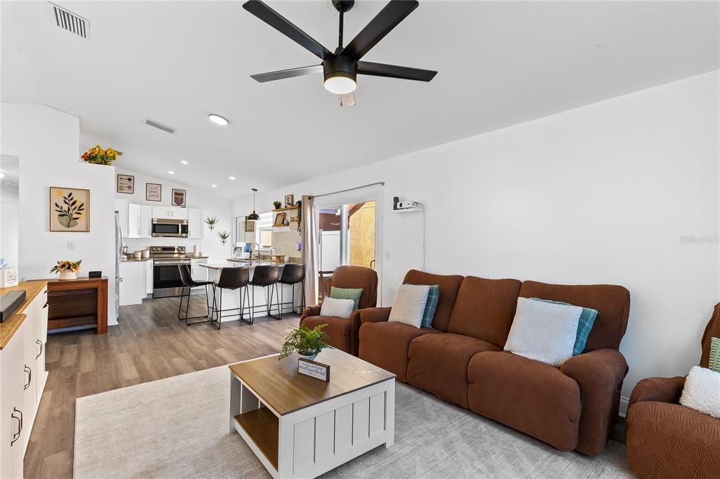 A living room with a brown sofa and coffee table opens into a kitchen area — 421 HORIZON DRIVE, WINTER SPRINGS, FL