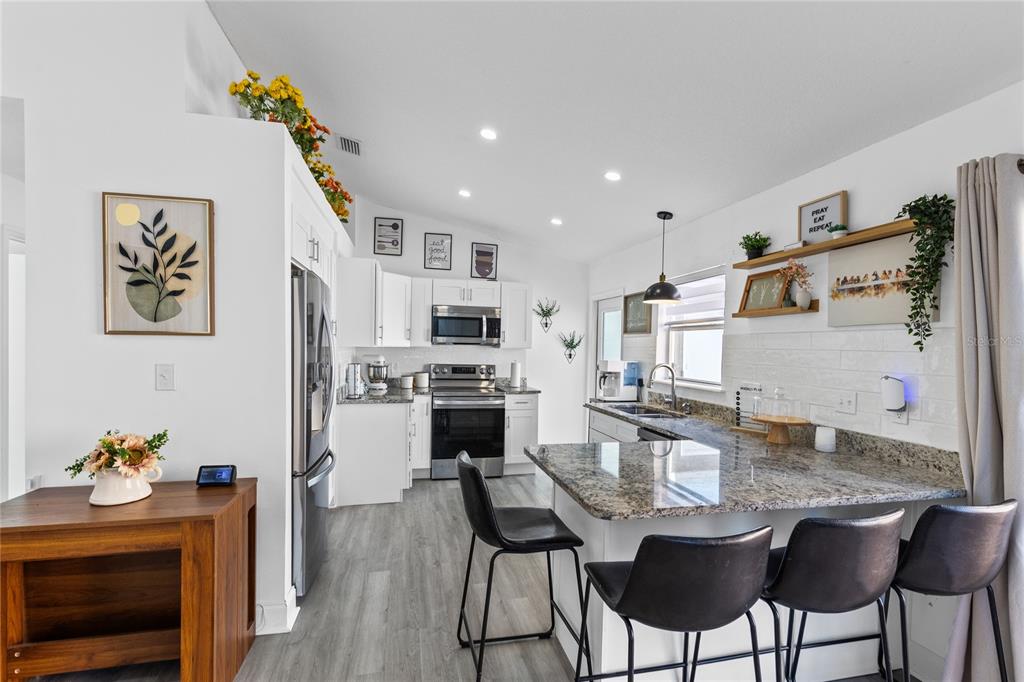 A modern kitchen features white cabinets, granite countertops, stainless steel appliances, and a breakfast bar — 421 HORIZON DRIVE, WINTER SPRINGS, FL