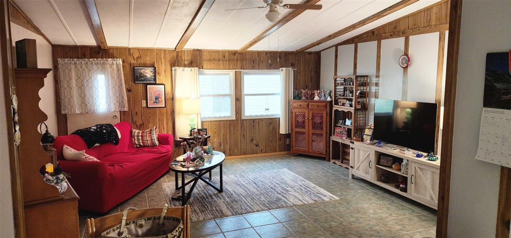 A living room features wood-paneled walls, a red sofa, a television, and tile flooring — 121 PINE TREE DRIVE, DEBARY, FL