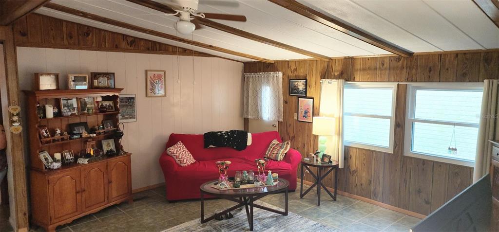 A living room features wood-paneled walls, a red sofa, a hutch, and a ceiling fan — 121 PINE TREE DRIVE, DEBARY, FL