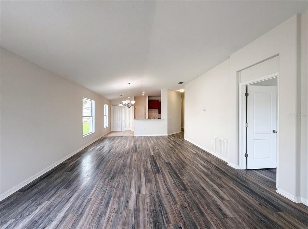 An open-concept living area features wood-look flooring, white walls, and a view into the kitchen — 1969 HAWKS VIEW DRIVE, RUSKIN, FL
