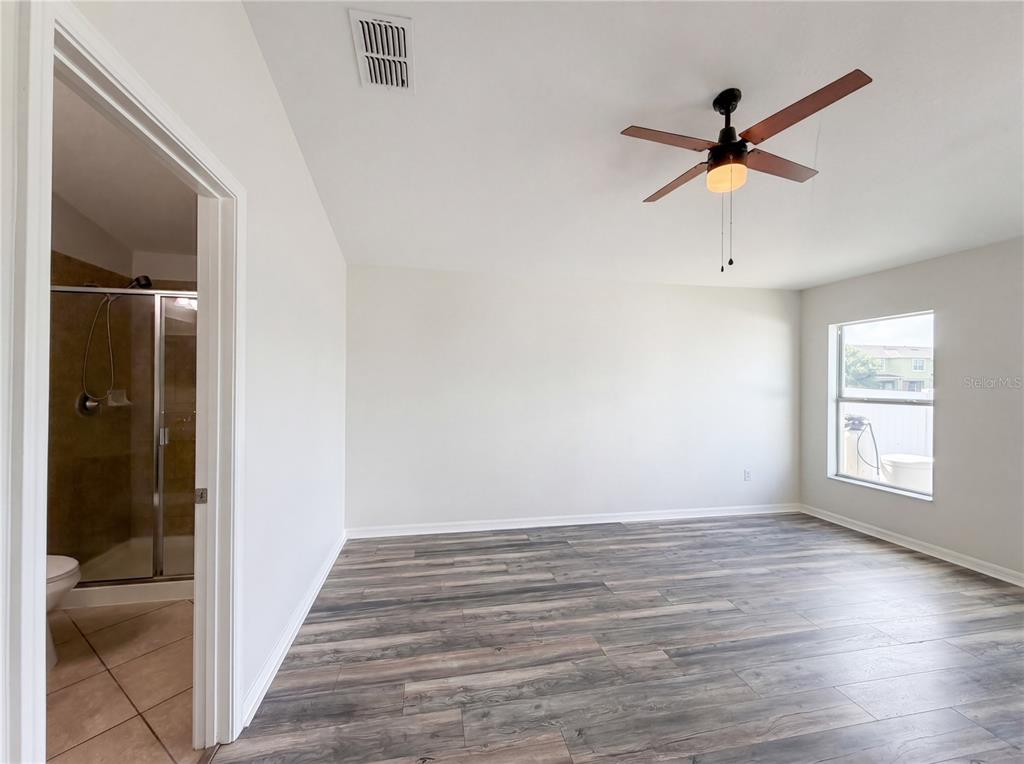 A bedroom with wood-look flooring, a ceiling fan, and an attached bathroom with a shower — 1969 HAWKS VIEW DRIVE, RUSKIN, FL