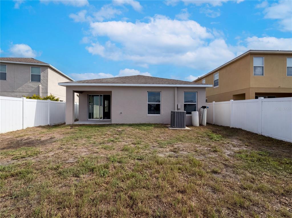 The rear exterior of a single-story house features a covered patio and a fenced yard — 1969 HAWKS VIEW DRIVE, RUSKIN, FL