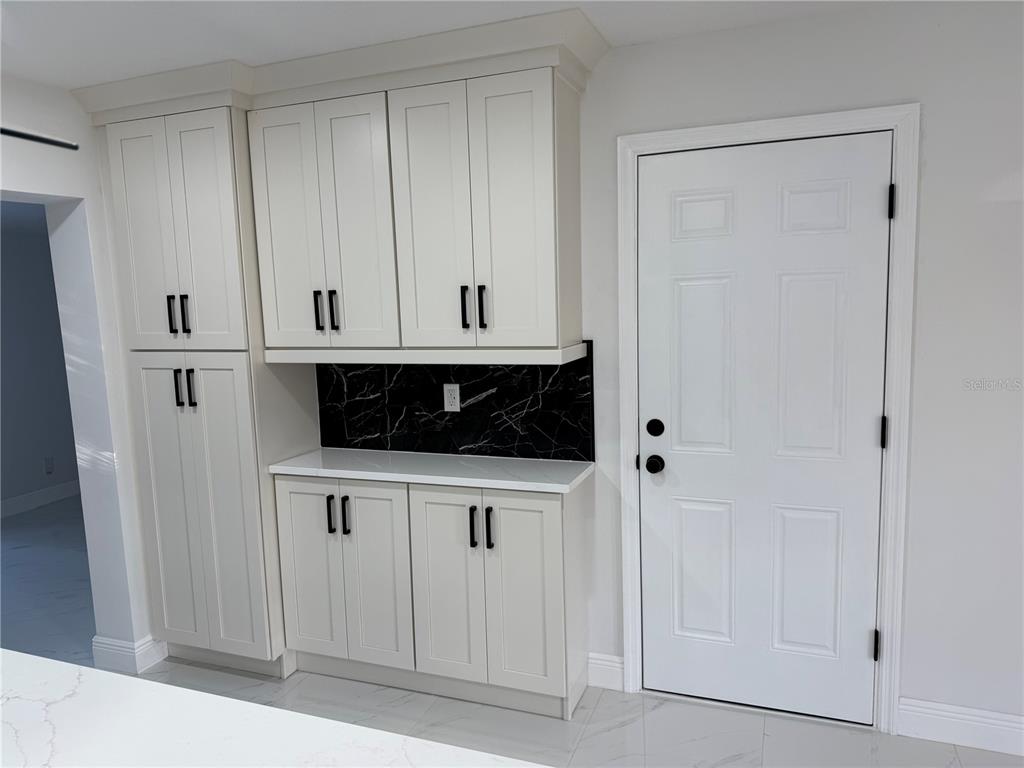 A kitchen area features off-white cabinets, a black marble backsplash, and a white door — 1457 MONTEGO LANE, ORLANDO, FL