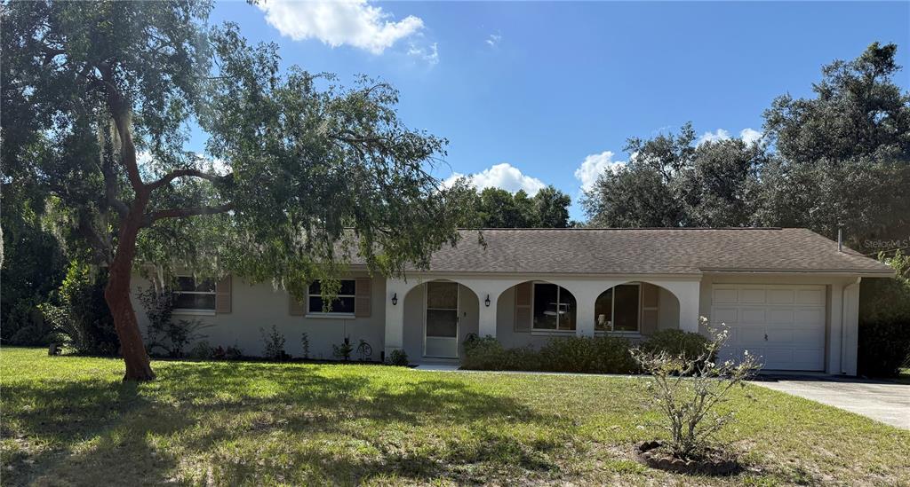 A single-story house with a beige exterior, arched front porch, and an attached garage — 12215 ORCHID LANE, THONOTOSASSA, FL
