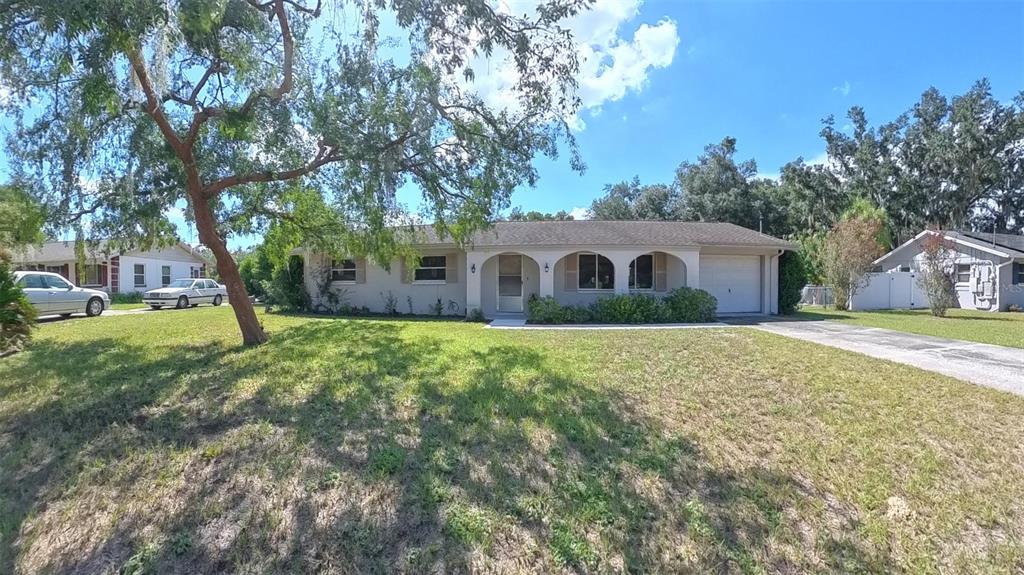 A single-story house with a beige exterior, arched entryway, and a one-car garage — 12215 ORCHID LANE, THONOTOSASSA, FL