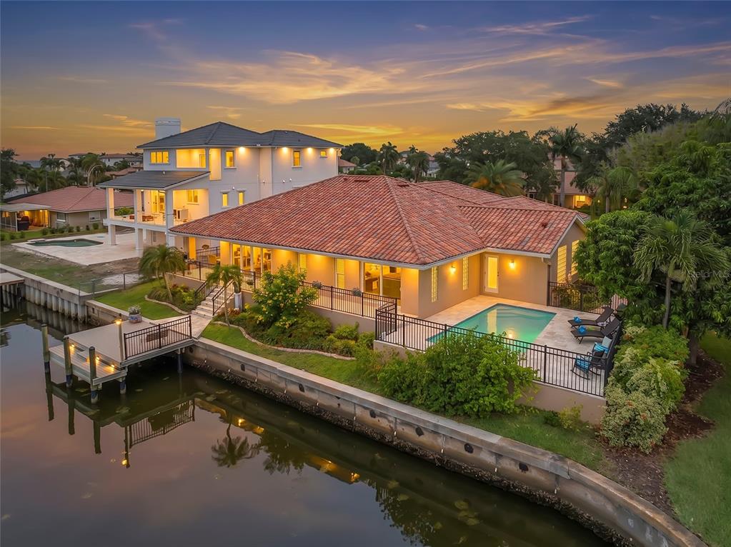 An elevated waterfront house with a tiled roof, a wooden dock, and a swimming pool — 2001 ILLINOIS AVE NE, ST PETERSBURG, FL