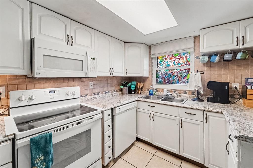 A living room with turquoise walls, a grey sectional sofa, tiled floors, and a ceiling fan — 8143 HIXTON DRIVE, PORT RICHEY, FL
