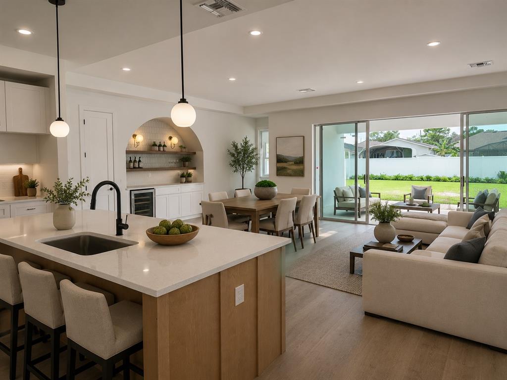 An open-concept kitchen and living area features a large island, dining table, and sliding glass doors — 18891 NETHERLAND STREET, ORLANDO, FL