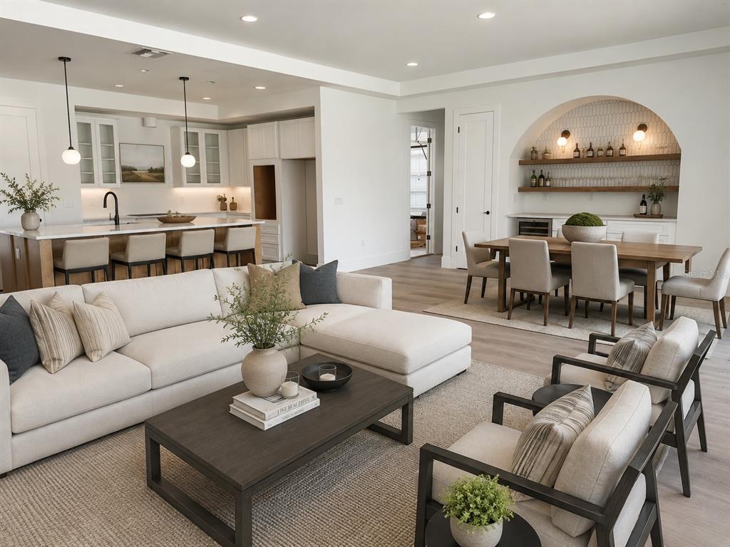 An open-concept living room, kitchen, and dining area featuring light wood floors and neutral furniture — 18891 NETHERLAND STREET, ORLANDO, FL