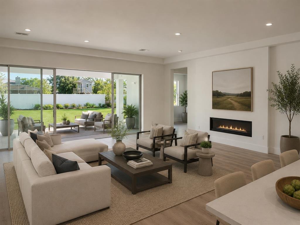 This living room features a linear fireplace, neutral furniture, and large sliding doors to a patio — 18891 NETHERLAND STREET, ORLANDO, FL