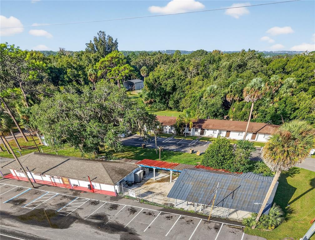 An aerial view shows a single-story building with a parking lot and a wooded background — 37415 STATE ROAD 19, UMATILLA, FL