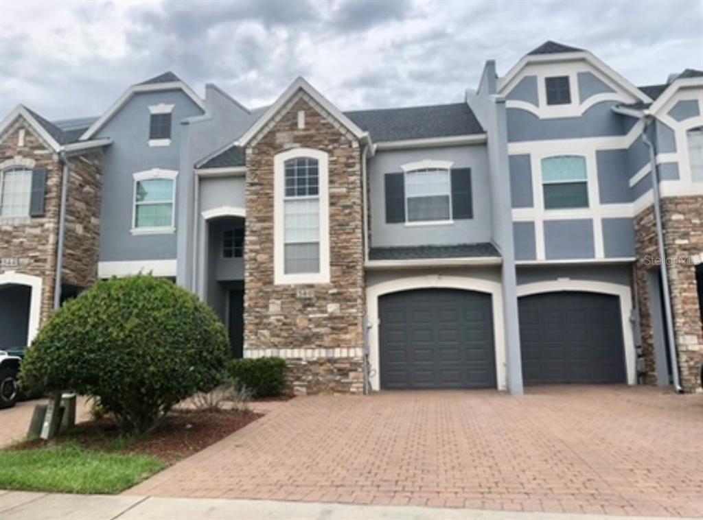 A multi-story townhouse exterior features stone veneer, gray siding, and two attached garages — 540 WOODLAND TERRACE BOULEVARD, ORLANDO, FL
