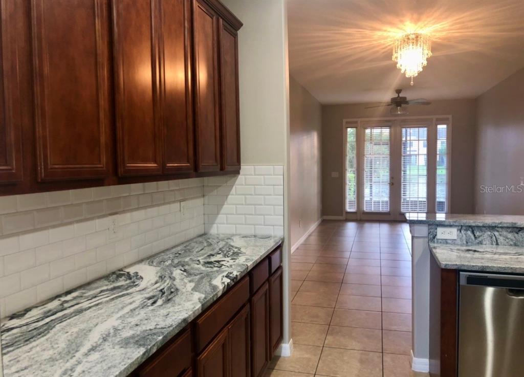 A kitchen features dark wood cabinets, white subway tile backsplash, and granite countertops — 540 WOODLAND TERRACE BOULEVARD, ORLANDO, FL