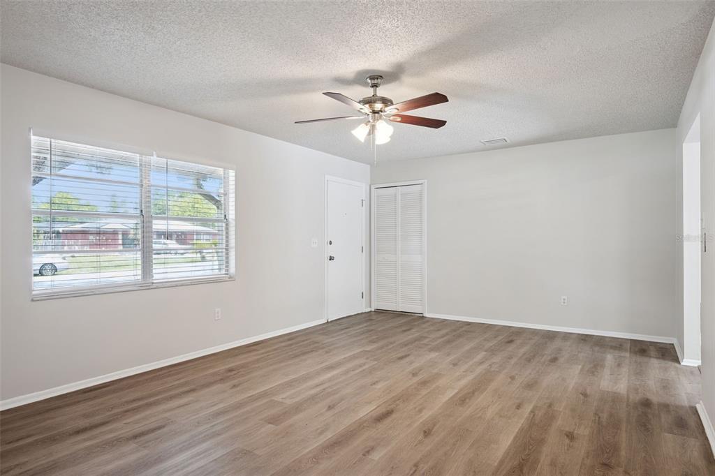An empty living room features light gray walls, wood-look flooring, a ceiling fan, and blinds — 111 BORADA ROAD, SANFORD, FL