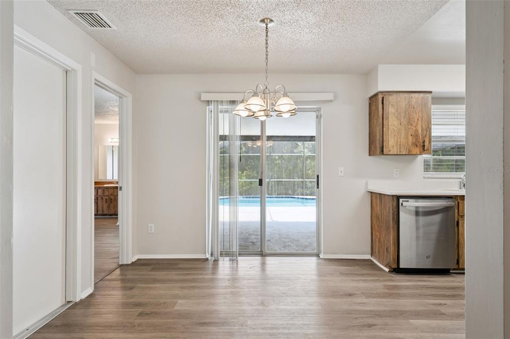 A dining area with wood-look flooring, a chandelier, and a sliding glass door to a pool — 111 BORADA ROAD, SANFORD, FL