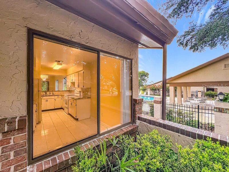 A view through a sliding glass door shows a kitchen with white cabinets and tile floors — 340 GOLFSIDE COVE UNIT 340, LONGWOOD, FL