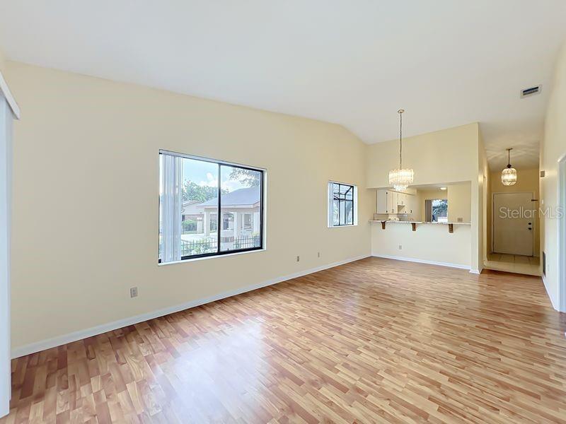 A bright living room features light-colored walls, hardwood flooring, and a pass-through to the kitchen — 340 GOLFSIDE COVE UNIT 340, LONGWOOD, FL
