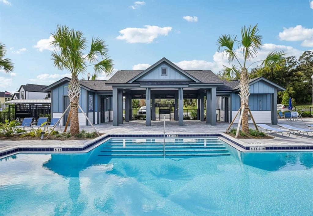A swimming pool sits in front of a blue clubhouse with a covered patio area — 5831 NATIVE OAK STREET, MOUNT DORA, FL