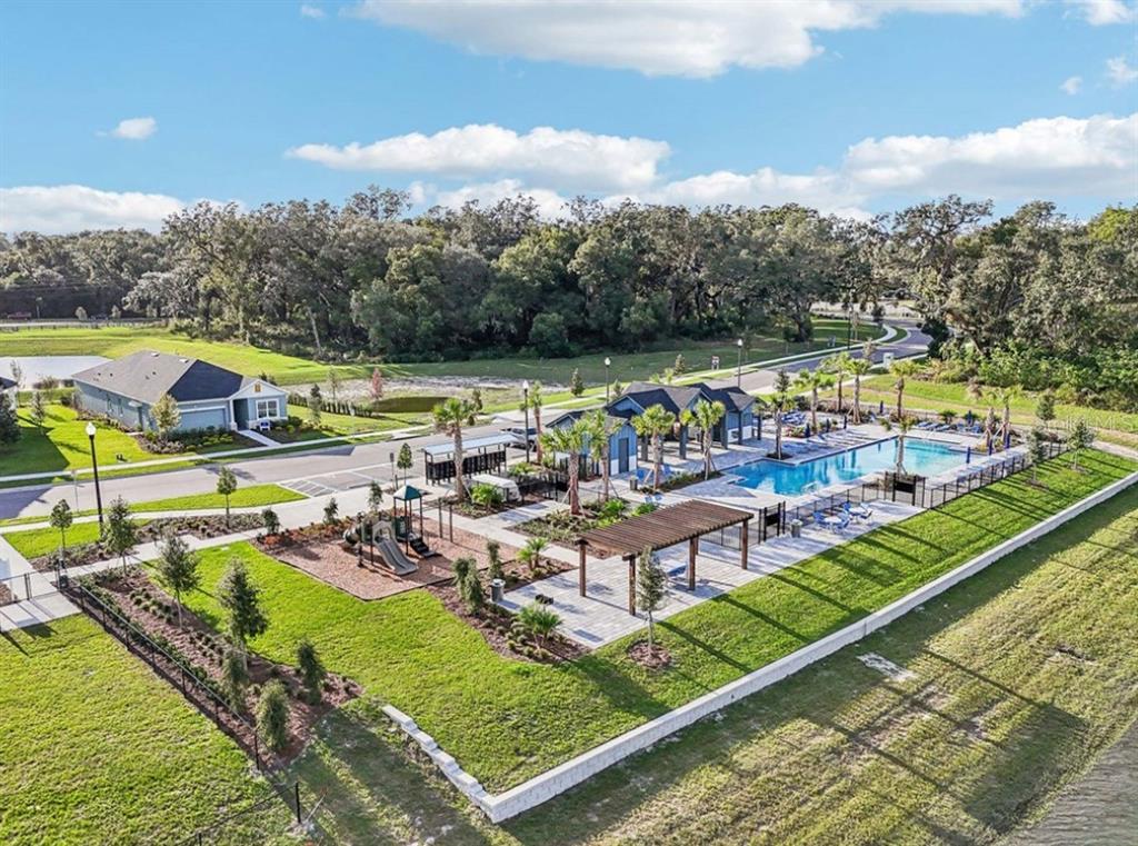 An aerial view of a community pool, playground, and clubhouse surrounded by green space — 5831 NATIVE OAK STREET, MOUNT DORA, FL