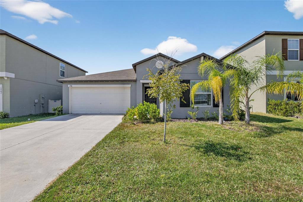A single-story gray house with a two-car garage and a front lawn with palm trees — 1748 RED LOOP, LAKELAND, FL