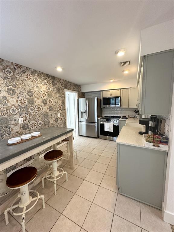A kitchen features a patterned tile accent wall, a long table, and light-colored cabinetry — 839 FLORIDA AVENUE, PALM HARBOR, FL