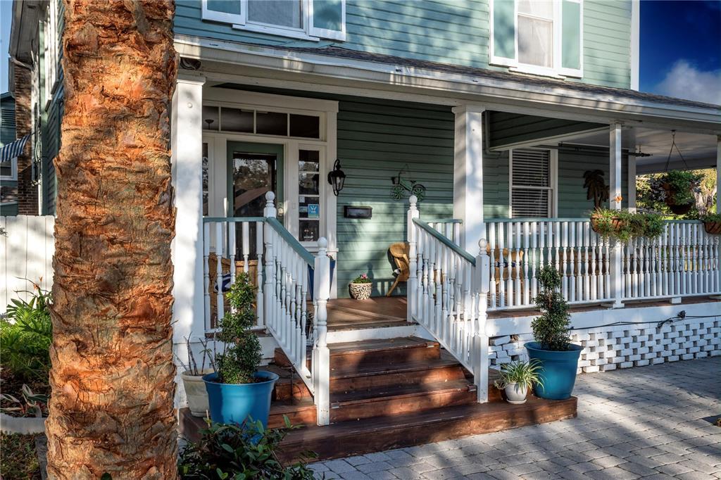 A wooden staircase leads to a covered front porch of a green house with railings — 304 15TH STREET W, BRADENTON, FL