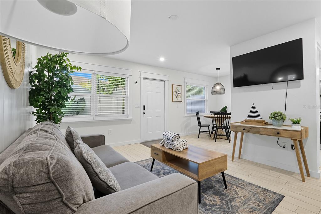 A living room features a gray sofa, a wooden coffee table, and a wall-mounted television — 3016 GULF DRIVE, HOLMES BEACH, FL