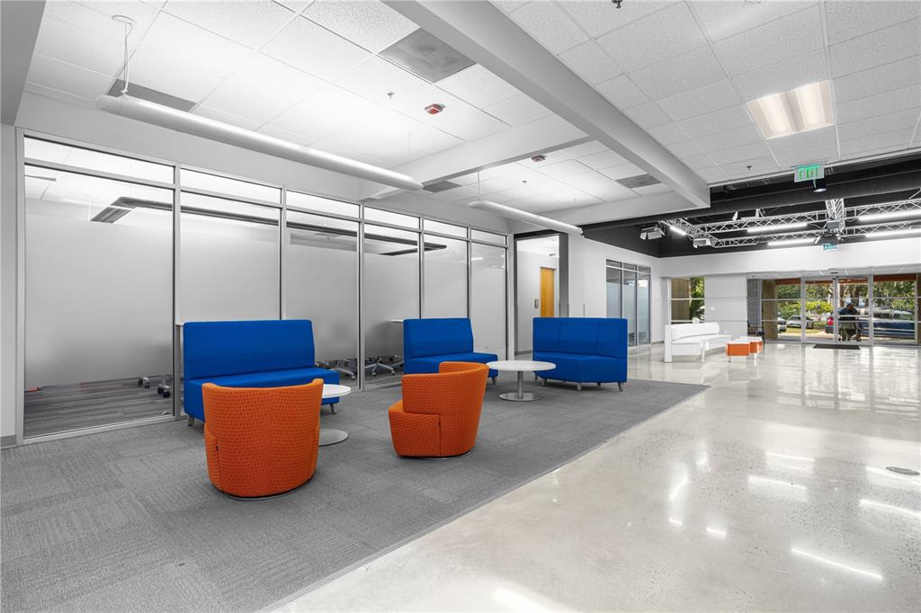 A modern office lobby features a seating area with blue sofas and orange armchairs — 7525 NW 4TH BOULEVARD, GAINESVILLE, FL