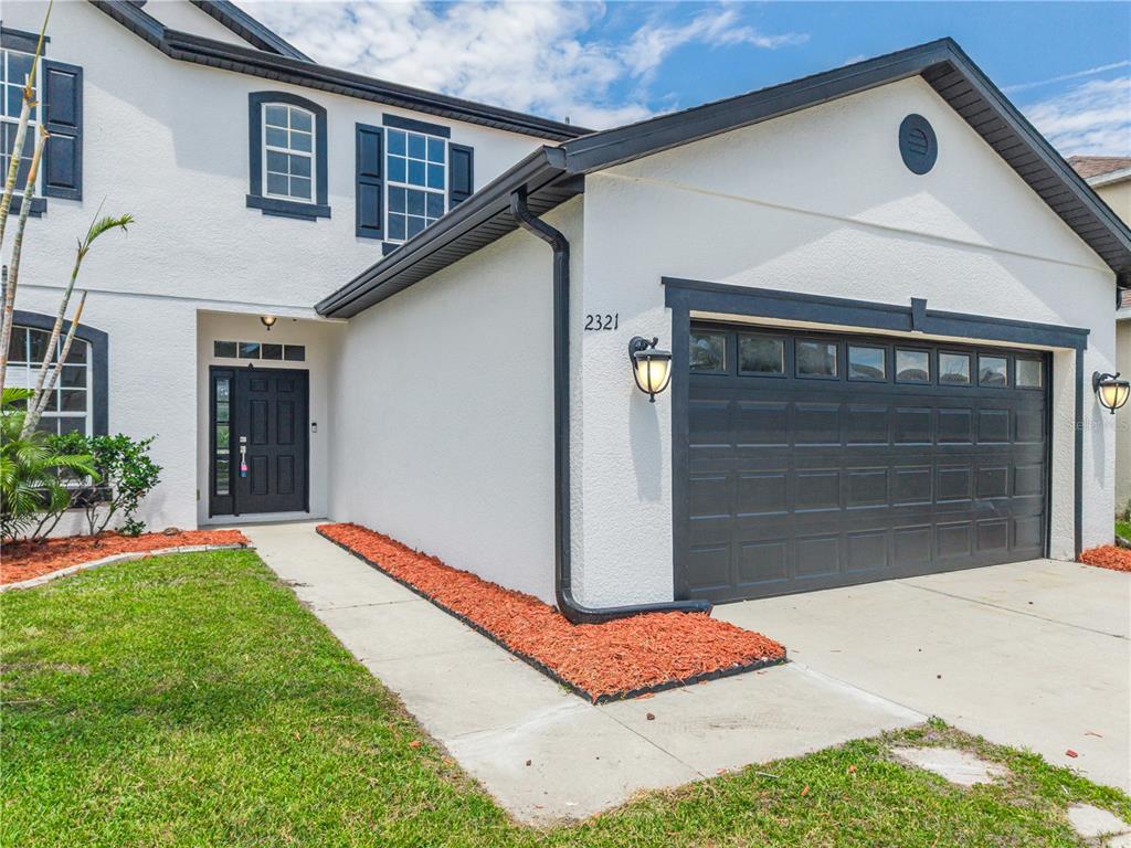 A two-story house with a white stucco exterior, dark trim, and a two-car garage — 2321 THE OAKS BOULEVARD, KISSIMMEE, FL