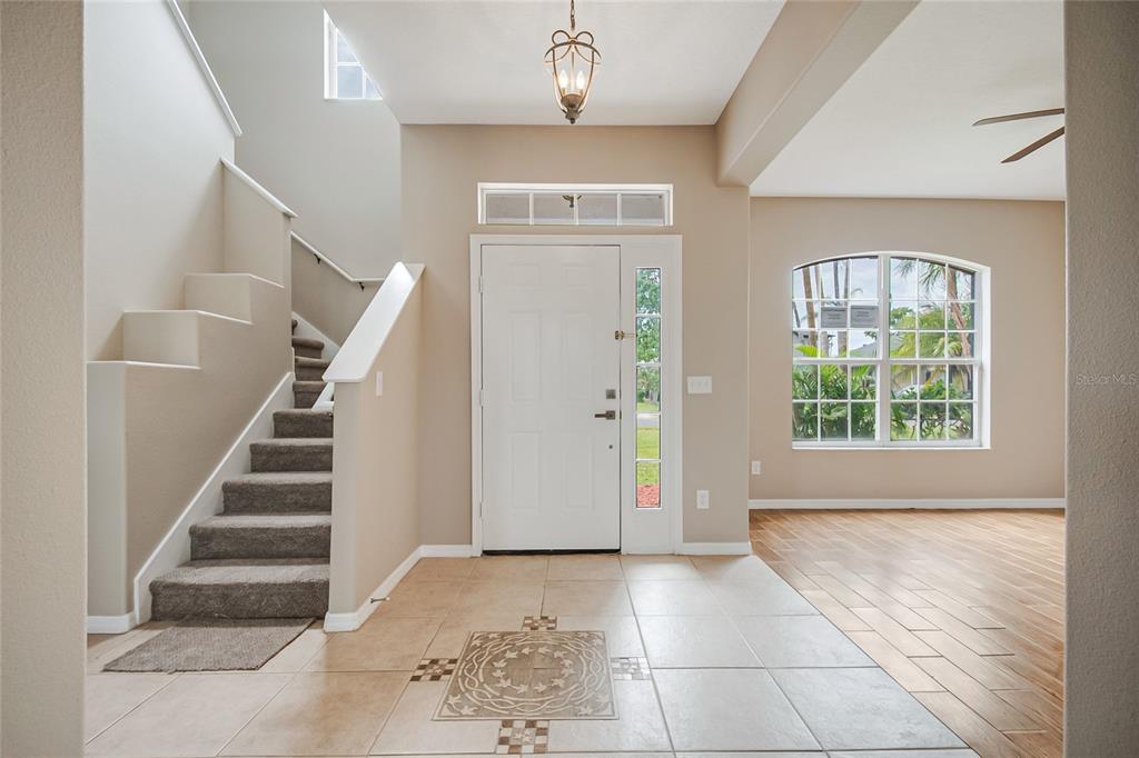 An entryway features a tiled floor, a carpeted staircase, and a white front door — 2321 THE OAKS BOULEVARD, KISSIMMEE, FL