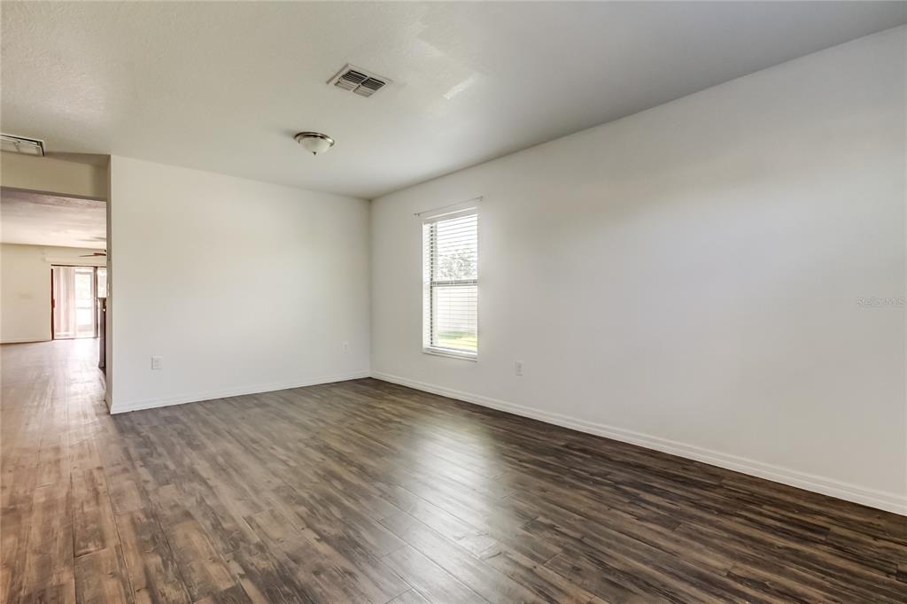 An empty room with wood-look flooring, white walls, a single window, and a ceiling light — 1739 CHATHAM GREEN CIRCLE, RUSKIN, FL