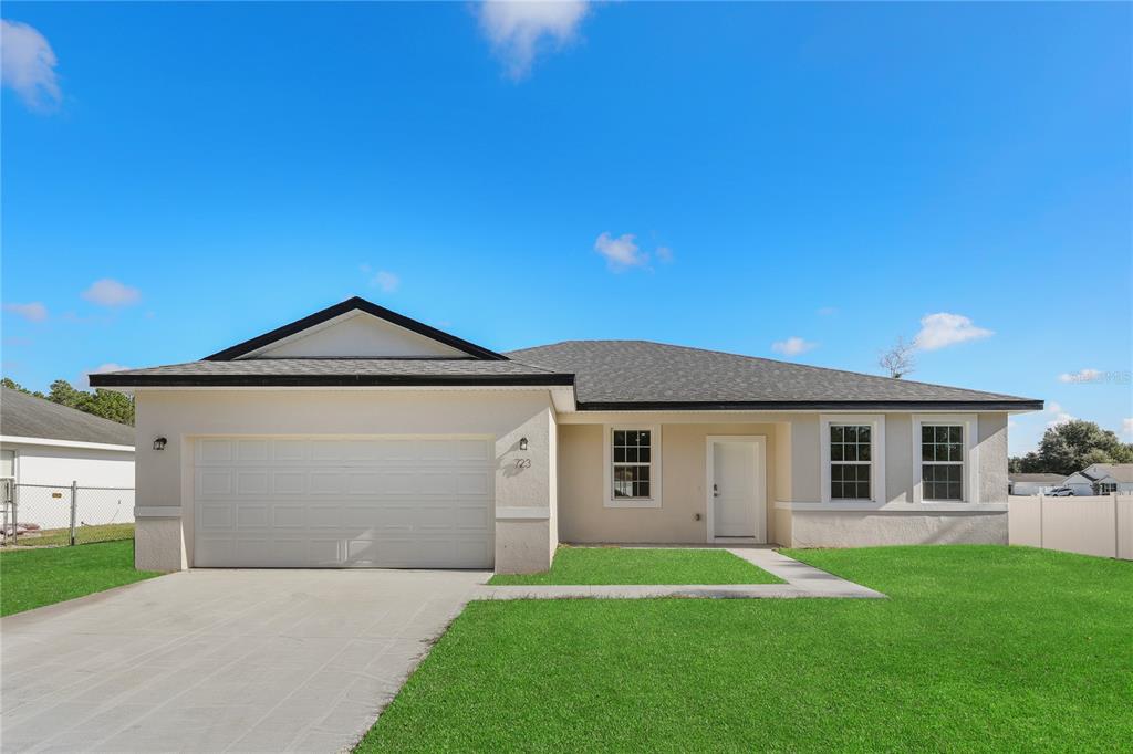 A single-story suburban house with a white stucco exterior, a garage, and a front lawn — 2681 SW 161ST LOOP, OCALA, FL