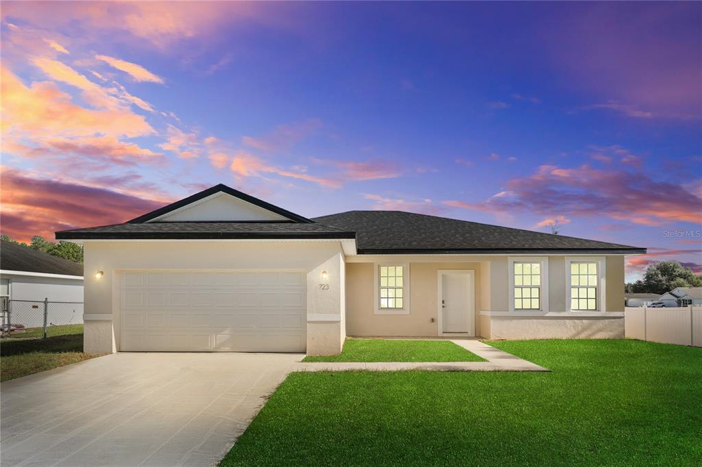 A single-story house with a white stucco exterior, a two-car garage, and a green lawn — 2681 SW 161ST LOOP, OCALA, FL