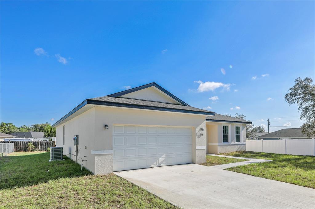 A single-story house with a white stucco exterior, a two-car garage, and a concrete driveway — 2681 SW 161ST LOOP, OCALA, FL