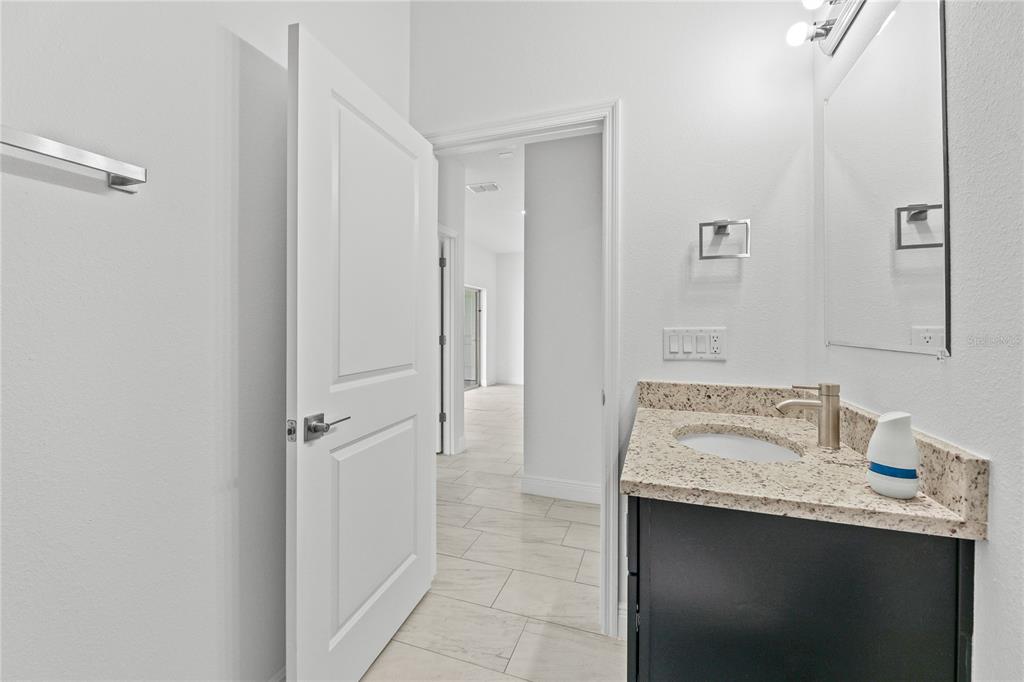 A bathroom features a dark vanity with a granite countertop, a mirror, and tiled flooring — 2681 SW 161ST LOOP, OCALA, FL